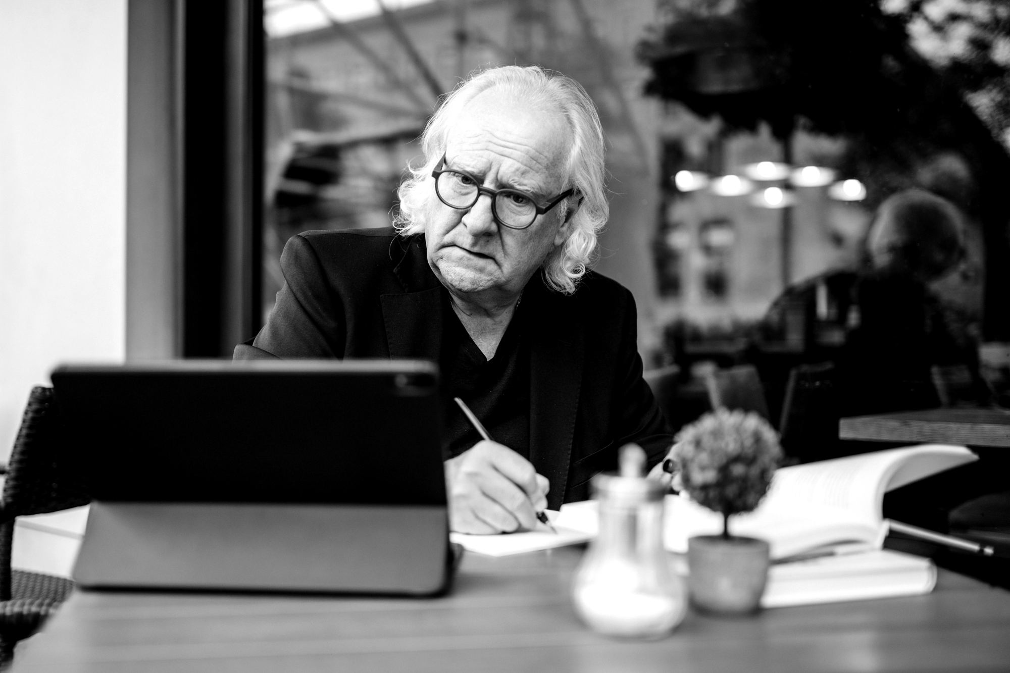 Brunello Gianella at the table, writing, with a tablet and books in front of him